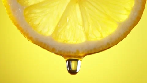 Super Slow Motion Macro Shot of Water Drop Falling from Lemon Slice on Yellow Stock Footage 151483085