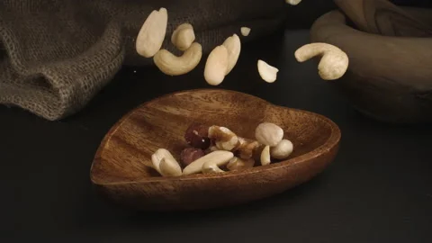 Super slow motion of Mix nuts falling into a wood bowl. 4k at 1000fps. Stock Footage 159553456