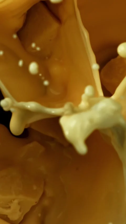 Super slow motion pieces of white chocolate fall into liquid chocolate . Filmed Stock Footage 335370580