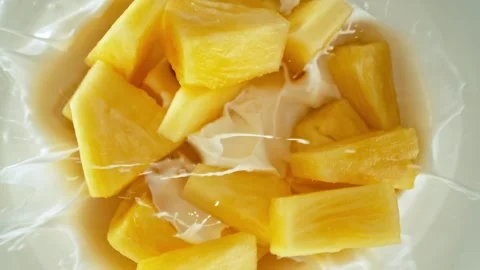 Super slow motion of pineapple pieces falling into yoghurt cream Stock Footage 273879478