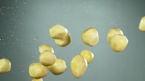 Super slow motion of potatoes flying up in the air with water splashes. Stock Footage 139814196
