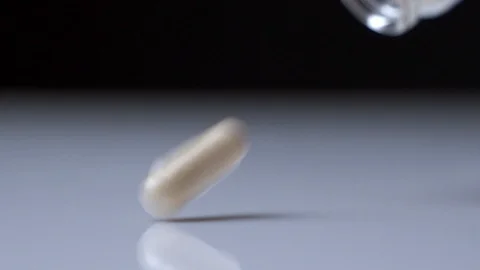 Super slow motion: Pouring capsule from bottle on black background Stock Footage 126906777