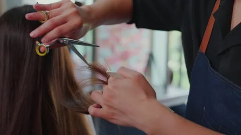 Super slow motion. Professional barber is using scissors to cut hair for youn Stock Footage 153964247