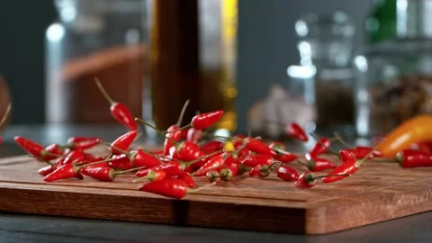 Super slow motion of rolling chilli peppers on wooden board. Stock Footage 166963123