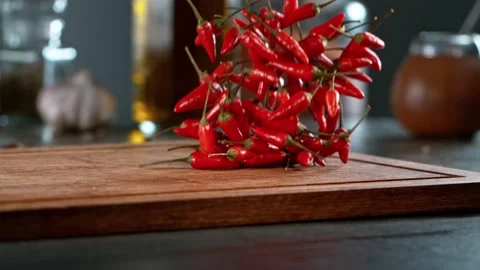 Super slow motion of rolling chilli peppers on wooden board. Video stock 166969565