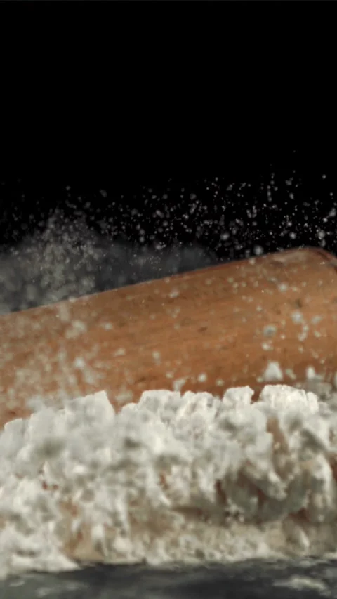 Super slow motion of the rolling pin falls on the table with flour. Filmed on a Stock Footage 335288413