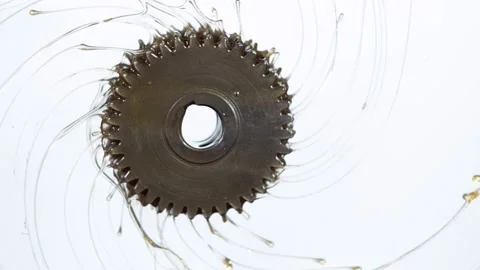 Super slow motion of rotating engine steel wheel with oil splashes on white Stock Footage 211710043