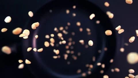 Super slow motion of rotating roasted peanuts falling onto a frying pan Stock Footage 282524322