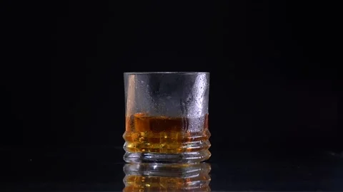 Super Slow Motion Shot of Droping the ice to the glass with Whiskey Stock Footage 153915374