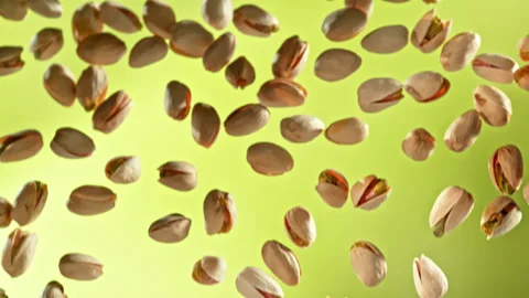 Super Slow Motion Shot of Falling Pistachio Nuts on Green Gradient Background at Stock Footage 312277781