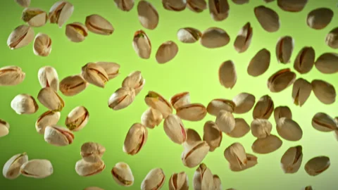 Super Slow Motion Shot of Falling Pistachio Nuts on Green Gradient Background at Stock Footage 313189056
