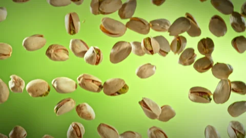 Super Slow Motion Shot of Falling Pistachio Nuts on Green Gradient Background at Stock Footage 313875445