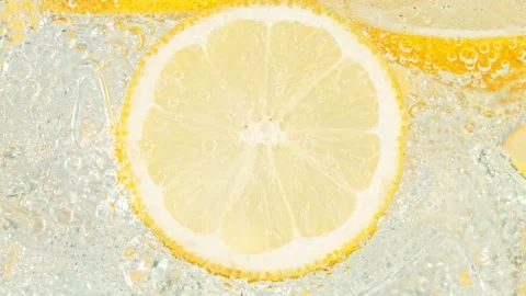Super Slow Motion Shot of Fizzing Water with Lemon Slices and Ice Cubes in Glass Vídeo Stock 157471065