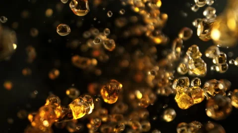 Super Slow Motion Shot of Flying Golden Liquid Drops Towards Camera on Black Stock Footage 313653282