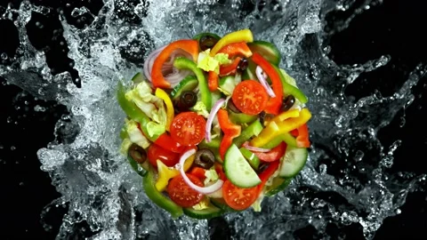 Super Slow Motion Shot of Fresh Salad Mix and Water Splash Isolated on Black at Stock Footage 228846905
