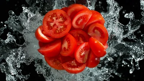 Super Slow Motion Shot of Fresh Tomato Cuts and Water Splash Isolated on Black Stock Footage 228855697