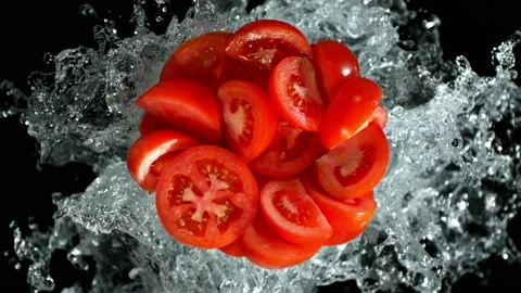 Super Slow Motion Shot of Fresh Tomato Cuts and Water Splash Isolated on Black Stock Footage 228955951