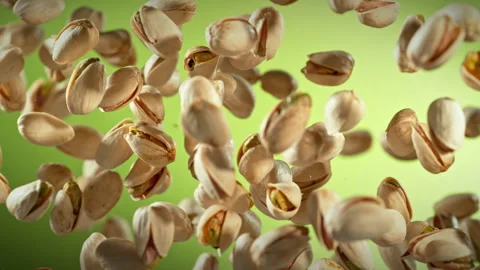 Super Slow Motion Shot of Fresh Pistachio Nuts Flying Up on Green Background at Stock Footage 309909055