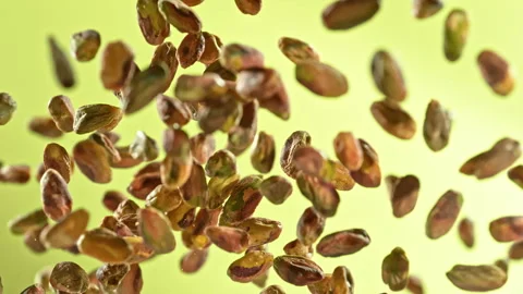 Super Slow Motion Shot of Fresh Peeled Pistachio Nuts Flying Up on Green Stock Footage 310655957