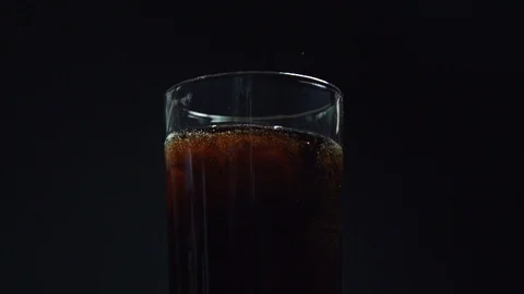 A super slow motion shot of ice being dropped into a glass of cola Stock Footage 87857266