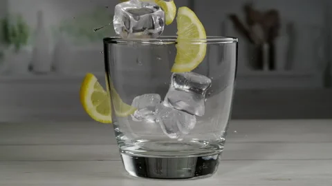 Super Slow Motion Shot of Ice Cubes and Lemon Slice Falling into Glass. Stock Footage 217656532