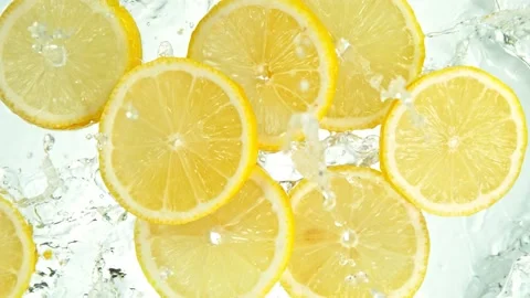 Super Slow Motion Shot of Lemon Slices Falling into Water on White Background at Video stock 137040902