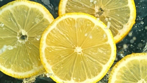 Super Slow Motion Shot of Lemon Slices Falling into Water on Black Background at Stock Footage 138790805