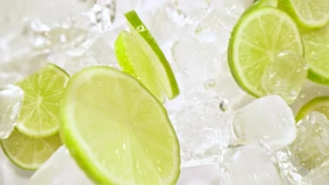 Super Slow Motion Shot of Lime Slices and Ice Cubes Falling on Black Background Stock Footage 149877429