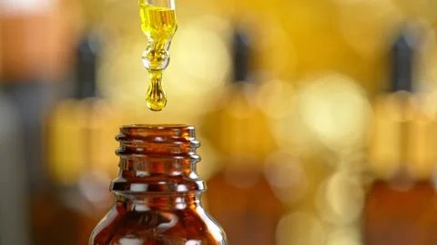 Super Slow Motion Shot of Oily Essence Drop into Phial on Golden Background at 스톡 동영상 159787248