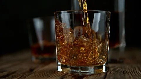 Super Slow Motion Shot of Pouring Whiskey into Glass with Ice Cubes at 1000fps Video stock 121893288