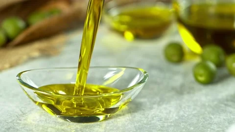 Super Slow Motion Shot of Pouring Fresh Olive Oil into Glass Bowl on White Stock Footage 133868749