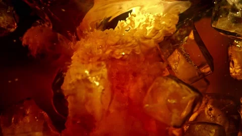 Super Slow Motion Shot of Pouring Cream into Cold Coffee Whirl with Ice Cubes at Stock Footage 153550581