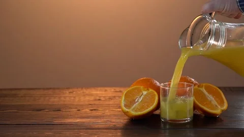 Super Slow Motion Shot of Pouring Fresh Orange Juice into Glass. Black Stock Footage 155649020