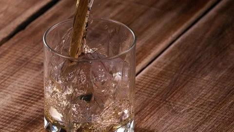 Super Slow Motion Shot of Pouring Whiskey over Big Ice Cube, 1000fps. Stock Footage 222697987