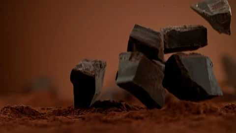 Super Slow Motion Shot of Raw Chocolate Chunks Falling into Cocoa Powder at Stock Footage 119688084