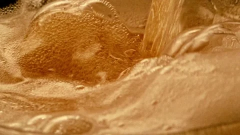 Super Slow Motion Shot of Rippling Fresh Beer Wave into glass, placed on blac Stock Footage 265768664