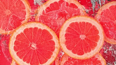 Super Slow Motion Shot of Splashing Fresh Pink Grapefruit Slices into Water at Video stock 160800730