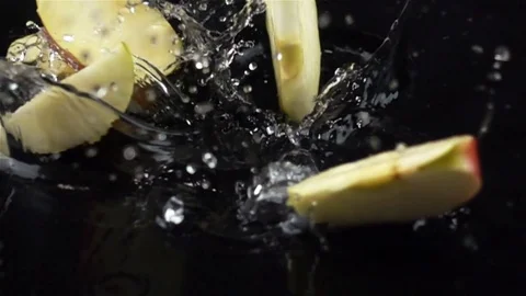 Super Slow Motion of Sliced Apple Falling with Water Splash on Black Surface Stock Footage 82238997