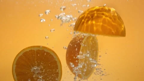 Super slow motion video of orange slices falling into water with a splash Video stock 274814285