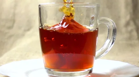 Super slow motion video of two sugar cubes falling into glass cup of black tea Vidéo 60024644