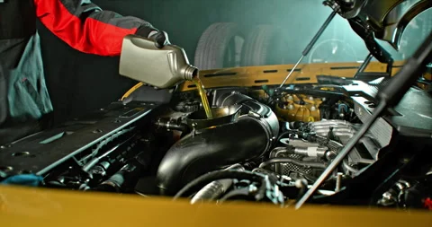 Super slow motion wide shot of mechanic pouring motor oil into car engine Stock Footage 332908916