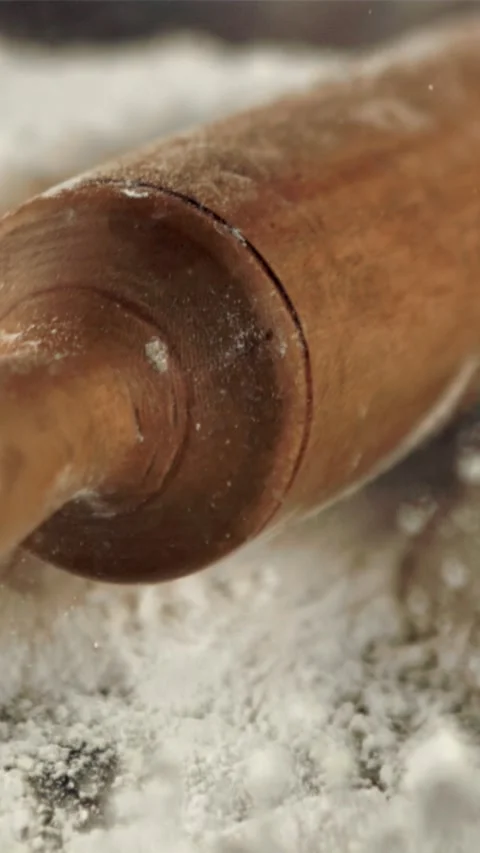 The super slow motion of the wooden rolling pin falls into the flour. Filmed on Stock Footage 335288746
