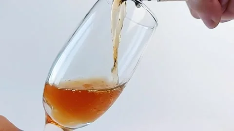 Super slow pouring of white wine into a glass at an angle on a white background. Stock Footage 168472482