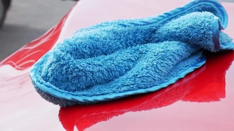 Super soft blue microfiber towel on a red car hood being pick up - extreme Stock Footage 321037048
