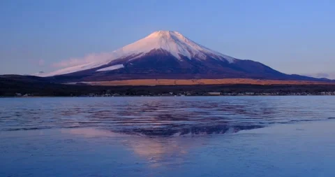 Superb view of Mount Fuji reflecting on frozen Lake Yamanakako with a blue sky Stock Footage 337451513