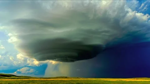 Supercell storm cloud rotating over green prairie landscape with rain shaft Stock Footage 343696053