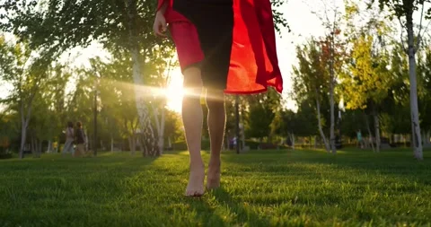 Superhero boy running barefoot across green lawn at sunset. Superhero costume Stock Footage 336185103