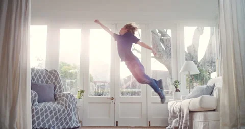 Superhero, child and jumping on couch in home, laughing and boy with energy in Stock Footage 331465206