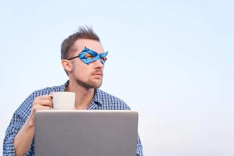 Superhero computer guy in blue mask using laptop outdoor holding coffee cup 写真素材