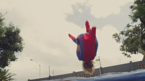 Superhero kid jumping on a trampoline Stock Footage 279219208